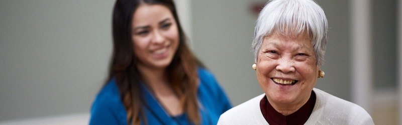 senior woman and caregiver smiling